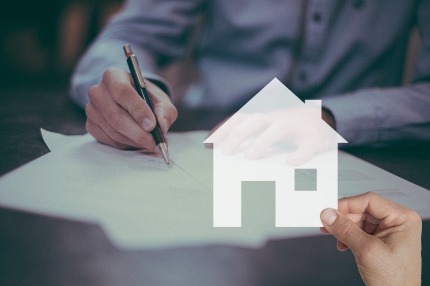 Person signing a contract with a digital image of a home overlayed.