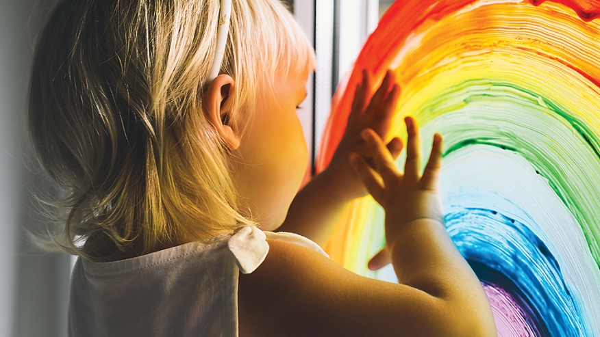 child touching window rainbow