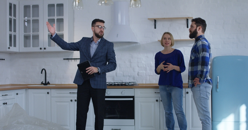 Medium shot of a real estate agent showing and explaining property to a couple (Photo credit: Getty Images/EvgeniyShkolenko)