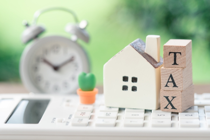 A model house model is placed on wood word TAX . as background property real estate concept with copy space for your text or design (Photo credit: Getty Images/supawat bursuk)