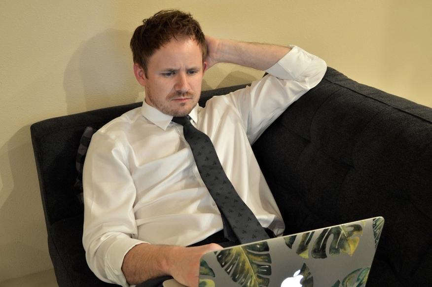 Man looking confused as he stares at his laptop.