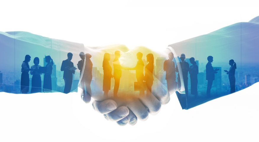 Photo of a handshake with people spread out. Photo credit: iStock.com/metamorworks