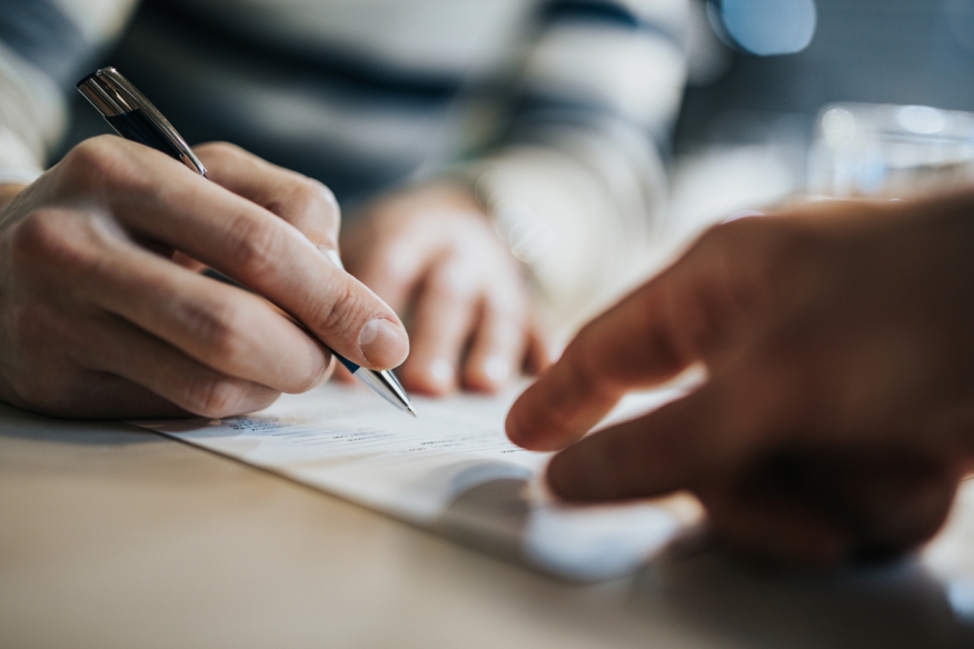 Person signing a mortgage application. Photo Credit: iStock.com/skynesher