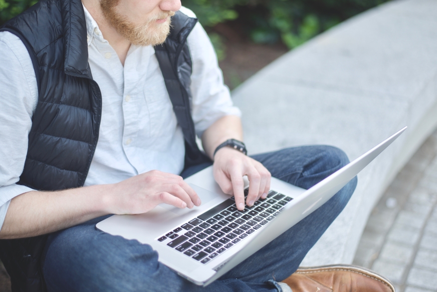 Man using laptop outdoors.