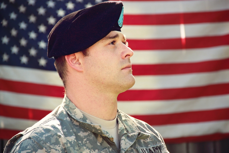 Soldier saluting with flag in background