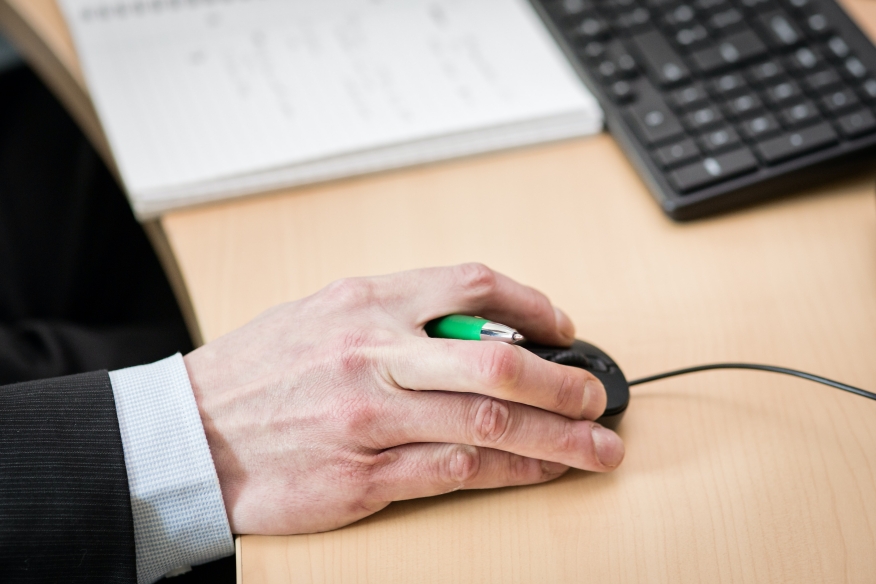 Hand holding a pen and computer mouse.