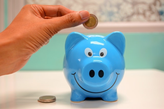 Person putting coin in blue Piggy Bank.