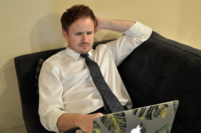 Millennial looking worried while staring at his laptop.