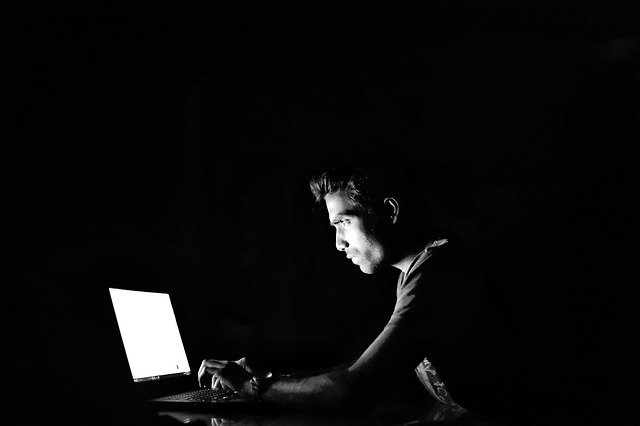 Person looking at computer screen in the dark.