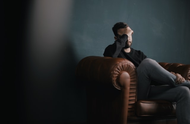 A man with his hand to his head stressed over bills.