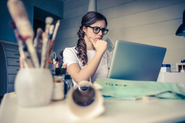 Woman staring at her laptop with pensive look.