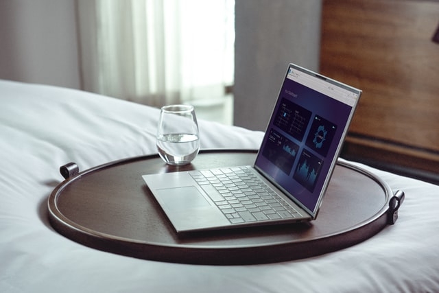 Computer and glass of water on a bed.
