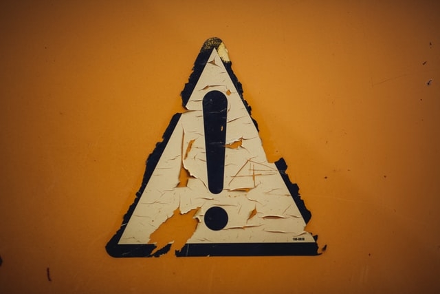 Aged caution sign with an orange background.