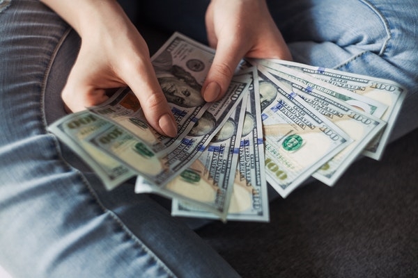 Photo of a person holding $1,000 worth of cash.