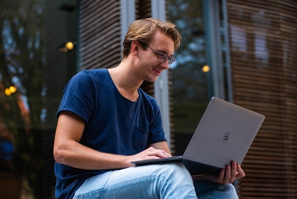 Millennial using a laptop on city steps.