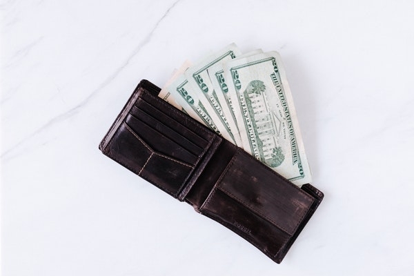 Photo of an open wallet with money coming out of it.