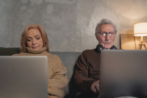 Elderly couple at home on their laptop.