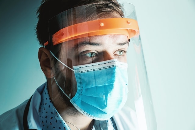 Photo of a man wearing a face mask and face shield.