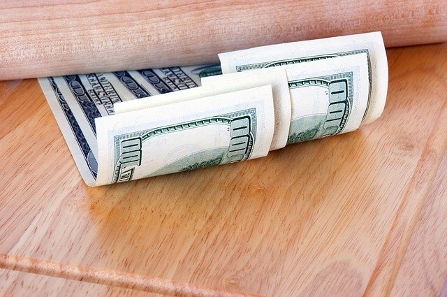 Photo of money tucked under a wooden structure.