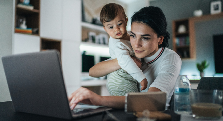 Mom holds her child while working from home