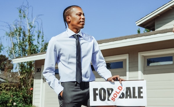 Man standing next to a house that's sold.