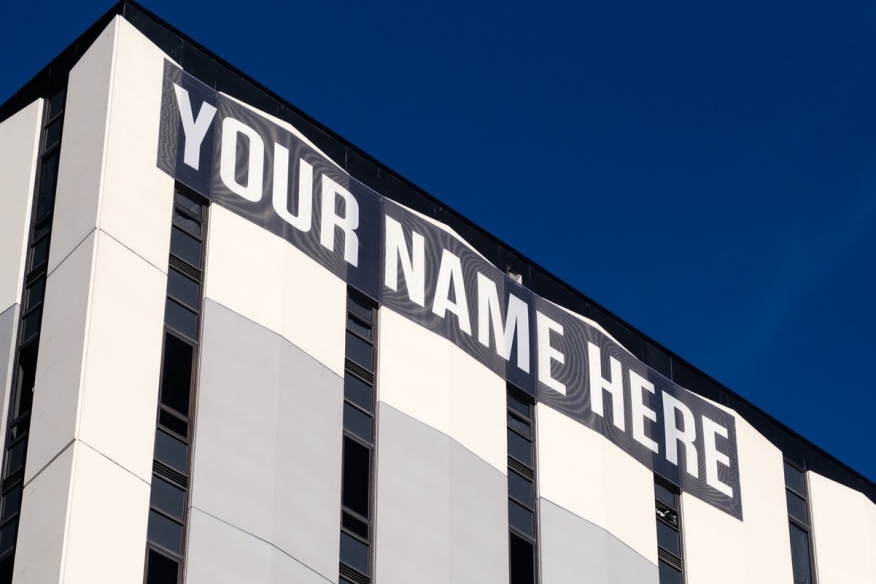 A sign on the side of a building reads, “Your name here”