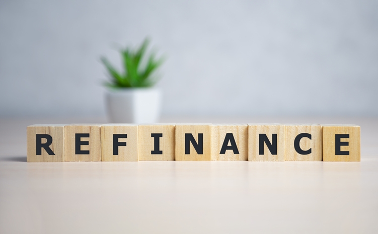 Photo of refinance spelled out with blocks and a plant in the background. Photocred: iStock.com/EugeneZvonkov.