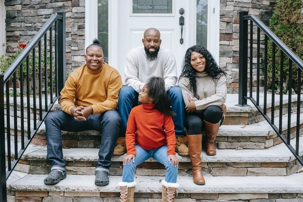 Photo of a family sitting on the steps of their home.