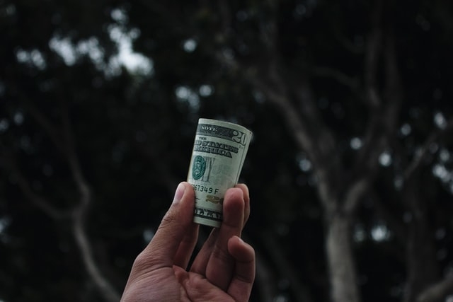Person holding a roll of money outdoors.