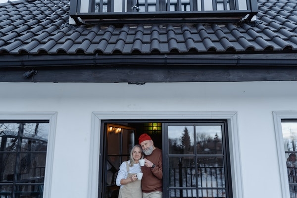 Senior couple having coffee outside their home.