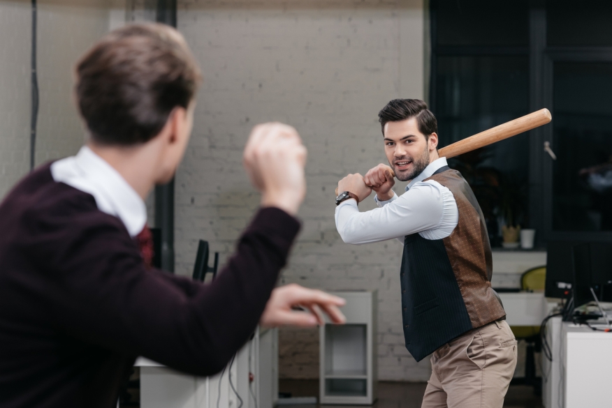 Two mortgage brokers play baseball inside an office.