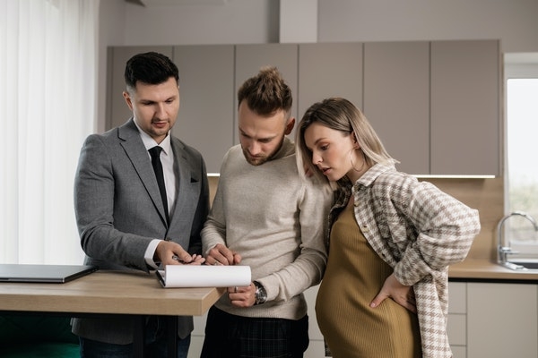 Photo of a young couple with their realtor.