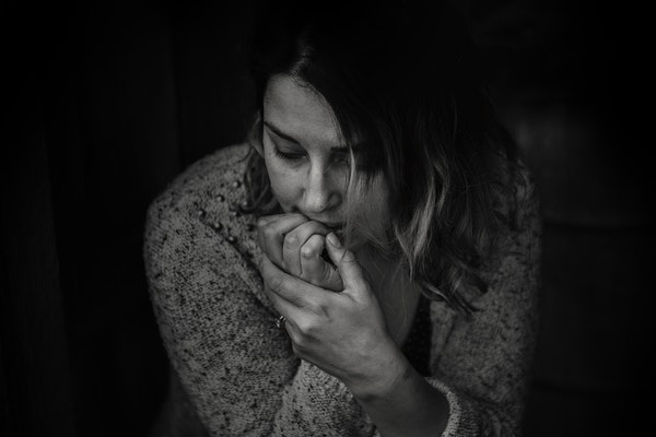Black and white photo of a woman looking nervous and scared.