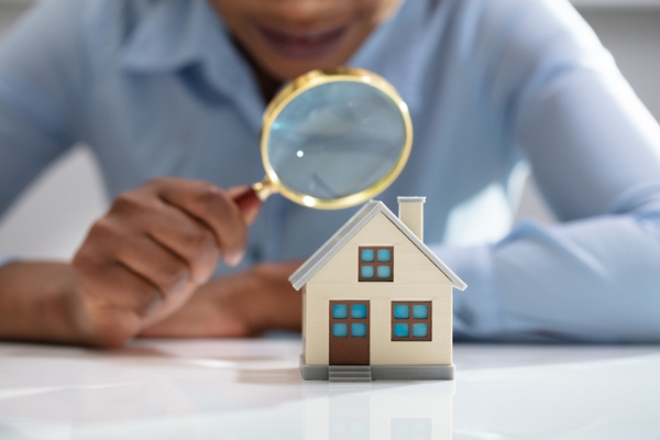 Photo of an appraiser looking at a miniature model home with a magnifying glass. Credit: iStockphoto.com/AndreyPopov.