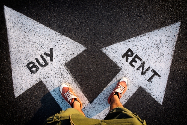Photo of a person standing on two arrows point in different directions with buy on one and rent on the other. iStockphoto.com/badmanproduction.