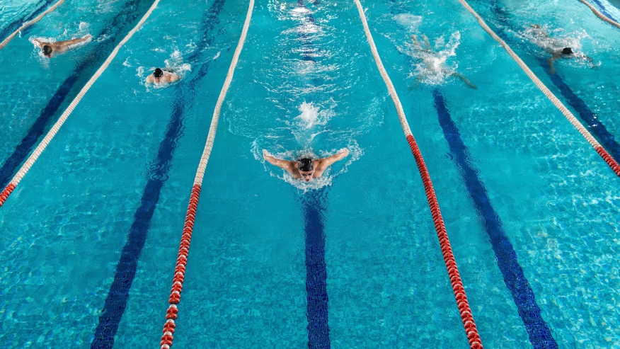 Five swimmers race with the center swimmer in the lead