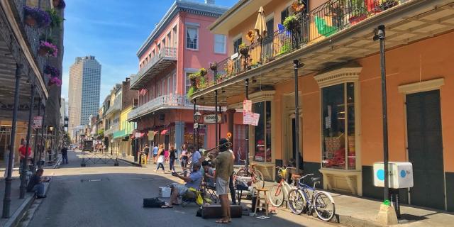 A group of musicians perform in front of pastel colored buildings on the streets of New Orleans, host city of the Ultimate Mortgage Expo
