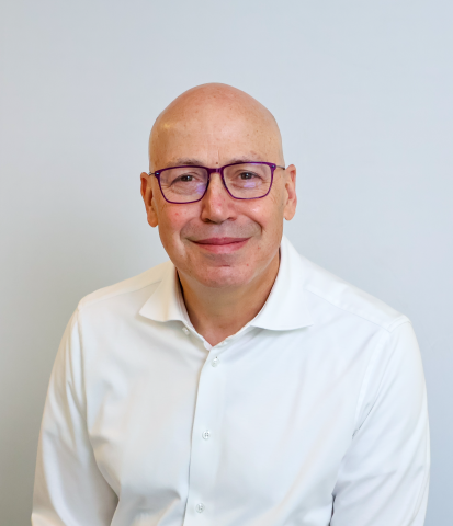 A white man with glasses and a white collared shirt