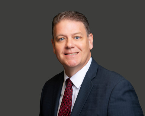 White man with blue eyes and gray hair in a navy suit