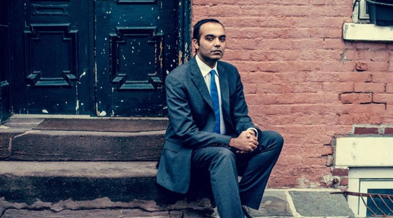 Rohit Chopra, commissioner of the Federal Trade Commission, sits on steps outside of a brick building.