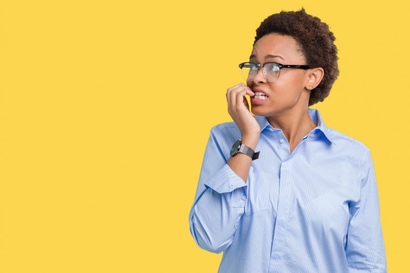 A young woman in business attire look to the side shy and worried.