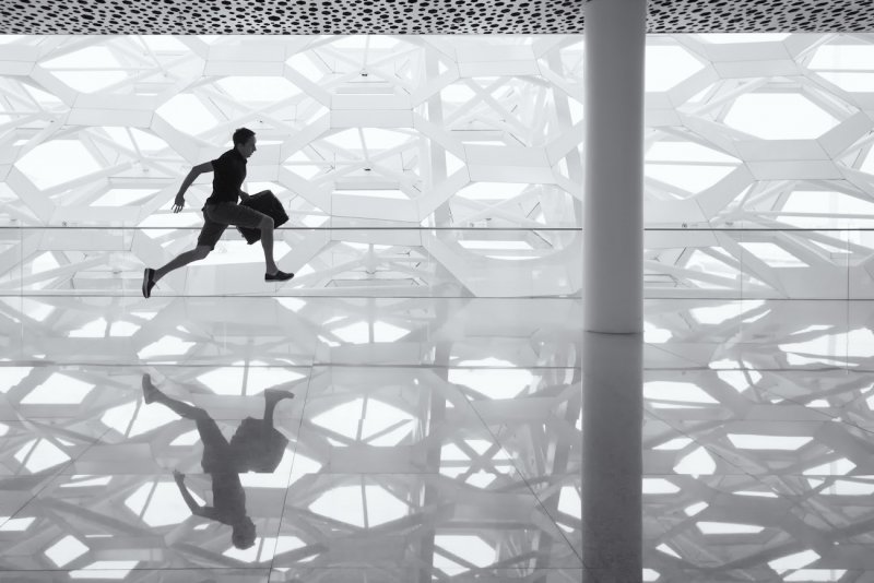 A man sprints holding a briefcase in greyscale