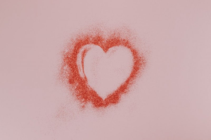 An outline of a pink heart made of glitter.