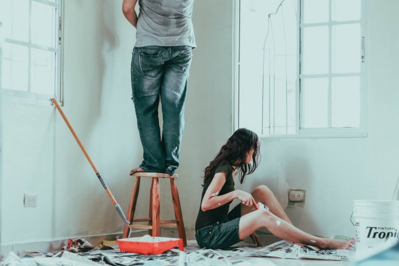 A young millennial man and woman are painting their newly bought home.