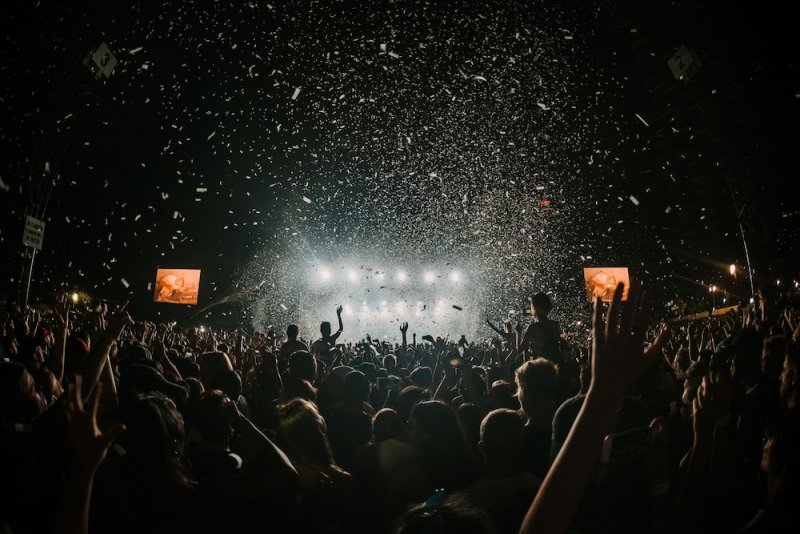 A large crowd at night rocks out to music at a festival.