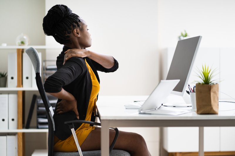 An office worker touches her back in pain