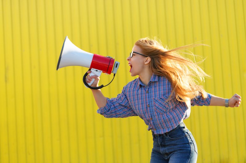 A young woman yells into a megaphone.