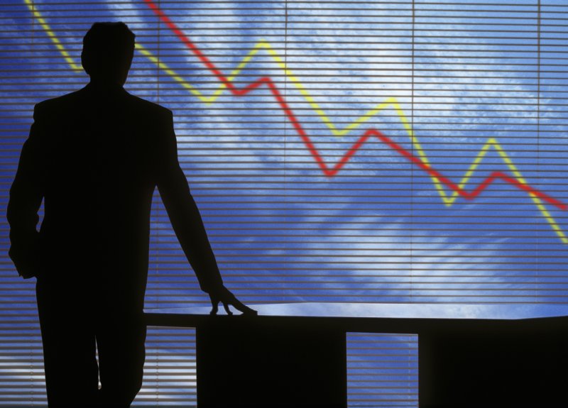 A man views a screen with lines charting downwards. 