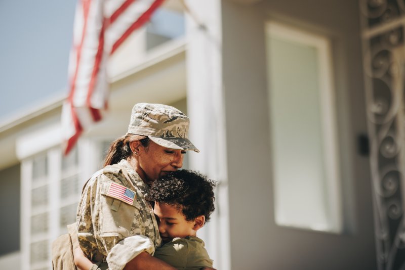 A veteran hugs her son in front of their home. 