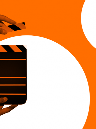 Hands holding a clapperboard, used to cue scenes on video sets, on an orange and white background